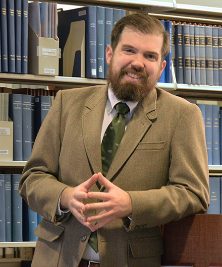Image of Joe V. posed in front of a bookshelf